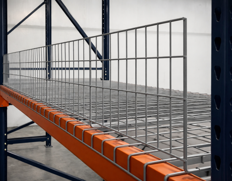 Metal shelving unit with orange safety rail in a warehouse setting