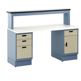 Heavy-duty industrial workbench with a white laminate top, dual pedestal base in blue, and beige locking drawer units. Features a raised upper shelf with a black edge for additional storage. Designed for manufacturing, assembly, or technical work environments
